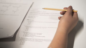 Papper och penna byttes ut mot dator på distans under urvalsproven. Vid Östra Finlands universitet rapporterades om tekniska problem med de elektroniska urvalsproven. En kvinna skriver ett inträdesprov. Man ser inte kvinnans ansikte.