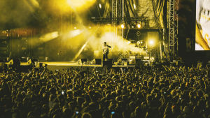 Räppäri Asap Rocky lavalla valtavan yleisömeren edessä Blockfesteillä. Kuva on lavan valojen vuoksi keltainen sävyltään.