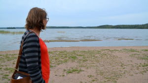 Maria Luoma-aho tycker det är synd att fåglarna tar över stranden. En kvinna står på en badstrand och tittar ut mot vattnet.