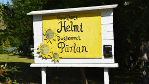 En gul skylt där det står päiväkoti Helmi, daghemmet Oärlan. 