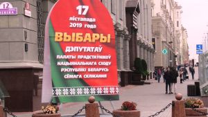 En valaffisch i centrum av Minsk. En stor valaffisch i grönt och rött med vit text i kyrilliska bokstäver står på en gata med stenhus i ljus sten. Också gatan är i vit sten.