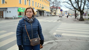 Kirsi Weckman-Toikkanen åker taxi varje vecka via jobbet. En kvinna står framför en korsning inne i en stad.