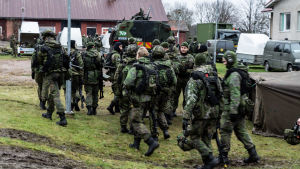 I Ebboskogarna övar hundratals soldater. Soldater framför ett militärfordon.