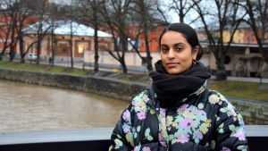Konstrundan är ett viktigt evenemang för konstnären Nayab Ikram. en kvinna med pakistanskt ursprung står på en bron invid aura å i höstväder iklädd svart tjock halsduk och blommig tjock jacka.