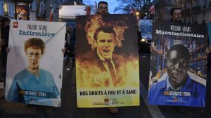 Demonstranterna håller i plakat med budskap som till exempel: Våra rättigheter till varje pris. Demonstranter håller upp plakat med bilder på en brinnande president Macron under protester i Paris.