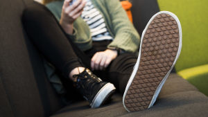 Många unga är tacksamma över att få tala om saken. En person sitter i en soffa och ser på sin telefon.