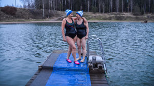 Arja Palmu och Marianne Kanerva njuter av vinterbad. Då man väl har börjat vill man ha mer och mer. Två glada kvinnor i mössa och baddräkt håller om varandra