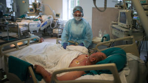 Coronavård i Ryssland. En man ligger på intensivvårdsavdelningen. En sköterska står invid hans säng.