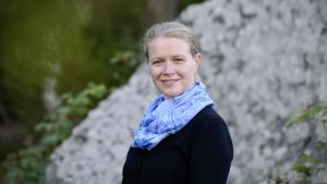 Ingrid Biese har själv hoppat av en karriär och trivs nu med forskaryrket. En kvinna iklädd en blå halsduk, står utomhus framför en stor sten.