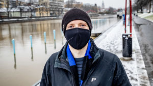 Mikael Kuisma undrar om alla som ska på teater och konserter ryms vid platsen. Man med svart munskydd och brun mössa tittar mot kameran. Aura å i bakgrunden.