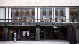 I oktober kunde man ännu se studerande i ett av Helsingfors universitets lunchrestauranger. Porthania-byggnaden som tillhör Helsingfors universitet. Vid fönstret kan man se några enstaka människor äta lunch.