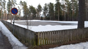 Här ska rinken i Ingå placeras - om inte de som protesterar vinner gehör och lyckas få en ändring i beslutet. I dagens läge fungerar sandplanen som bollplan och – då vädret tillåter – skridskoplan vintertid. Vy över sandplan med staket i runt.