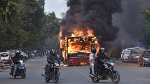 Demonstranter har tänt eld på flera bussar i protest mot den nya medborgarskapslagen. Bilden är tagen i New Delhi den 15 december. Bild på några motorcyklister som kör förbi en brinnande buss i New Delhi.
