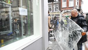 Måndagskvällens upplopp skapade förödelse i Den Bosch. En man flyttar en söndrig fönsterruta.