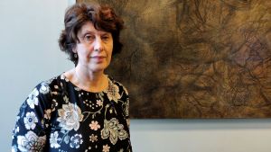 Minna Piispa på Justitieministeriet säger att man nog måste göra något. kvinna står framför en brun tavla