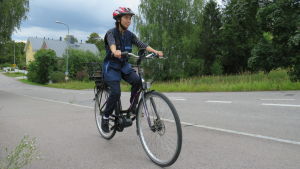 Suong Dang jobbar inom hemvården och hon cyklar till klienten med elcykel. Hemvården i Lojo har sex elcyklar på olika håll i staden. Kvinna cyklar på asfalterad väg.