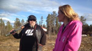 Birgitta Isaksson, i rödlila jacka En man som håller ett gevär diskuterar med en kvinna