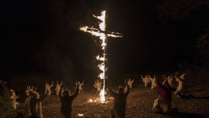 Brinnande kors ger bra publicitet vet Ku Klux Klan-medlemmarna i Colorado Springs. Ku Klux Klan-medlemmar knäböjer inför ett brinnande kors.