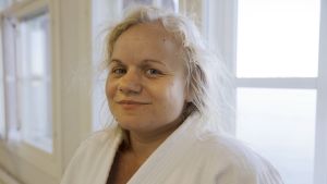 Aikidossa ei kilpailla, vaan päämääränä on harjoittelu itse. Seuraava vyökoe on Kikka Niittyaholla kuitenkin jo suunnitteilla.. Kikka Niittyaho nojaa ikkunaan aikidopuku päällään ja katsoo kameraan.