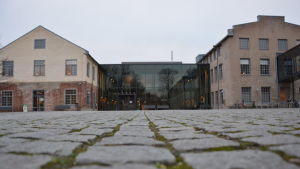 Största delen av föreläsningarna ordnas nu på distans. Arkens mittgård, fyrkantig stenläggning på marken. Gråmulet väder.