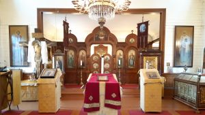 Här framför altaret brukar långborden dukas upp efter påskgudstjänsten i Hangö ortodoxa kyrka. Rött och guld dominerar interiören i Hangö ortodoxa kyrka. Kyrkoväggarna är vita.
