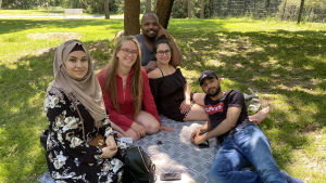 Arrangörerna för evenemanget och kampanjen. Från vänster: Afrah Al Bayaty, Nana Blomqvist, Mohamed Yousif Ibrahim, Hannaneh Mahmoudian och Shahin Ahmad. Arrangör Mohamad Sheik Murad är inte med på bild. En grupp människor sitter ute i en park på sommaren.