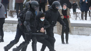 Polisen släpade iväg en Navalnyjsupporter i S:t Petersburg i januari. Poliser i kravallutrustning släpar på en ung kvinna på en snöig gata.