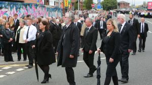 Flera nuvarande och tidigare ledare för det republikanska partiet Sinn Féin trotsade coronarestriktionerna då den legendariska IRA-aktivisten Bobby Storey begravdes i Belfast. I främsta ledet Sinn Féins nuvarande ledare Mary Lou McDonald, den tidigare ledaren Gerry Adams och partiets vice ordförande Michelle O'Neill. Svartklädda personer i ett begravningståg.