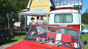 Bilen som bland annat fått följa med till Nådendal under sommaren. Sami Tikkanen vid en av sina gamla bilar och en husvagn framför Café Classic Garage i Snappertuna.