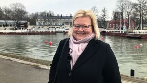 Anne Sjöström är museichef vid Nådendals museum. Anne Sjöström står vid gästhamnen i Nådendal med Brunnshuset i bakgrunden