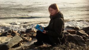 Hannan kirjokansi -blogin pitäjä lukee kirjaa Oritkarin talvisella rannalla.