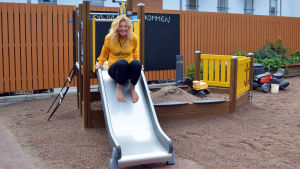 Marika Johansson gör ett provåk i den nya rutschkanan som ska göra tillvaron för barnen lite roligare. en kvinna tänker åka ner för en rutschkana i en liten lekpark