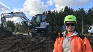 Rondellen har tidigare kritiserats för dålig sikt på grund av den höga växtligheten. Kvinna i reflexrock och hjälm står vid en uppgrävd rondell och ler.
