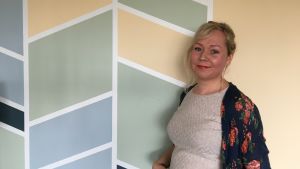 Anne Nickström skriver bloggen Singelmamman. Kvinna står vid vägg med grafiskt mönster.