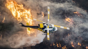 En brandhelikopter flyger ovanför branden i stadsdelen Bel-Air, Los Angeles på onsdag morgon, lokal tid.