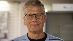 Martti Lilja är ledande övertandläkare inom vårdsamkommunen Soite. Han har inte sett en så allvarlig kösituation på årtionden. Mansperson i ljusblå tröja och glasögon tittar leende in i kameran.