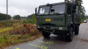 Västra Nylands tingsrätt bekantade sig med olycksplatsen. Ett grönt militärfordon på en asfalterad väg i närheten av ett järnvägsspår.