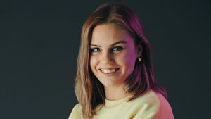 Hanna hoppas lyssnarna tar tillfället i akt och kommer med önskemål till podden. hanna bär en ljusgul collegetröja och har armarna i kors