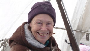 Riitta Airos sitter i sin segelbåt, som ännu är uppe på land och täckt av vit presenning