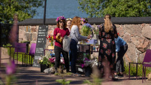 Rajka Kavonius (i röd skjorta) gjorde sin egen midsommarkrans. Stadin juhannus -festivaali Lonnan saarella Helsingin edustalla