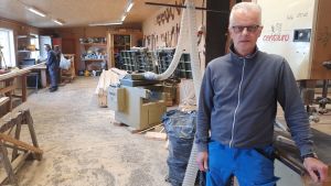 Det är stor skillnad på arbetstakten nu mot ifjol, då personalen var mindre, märker arbetsledaren Max Lassén. en man i snickarkläder står intill en bandsåg i ett snickeri