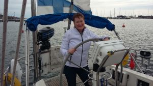 Äntligen går Tina Hellstens dröm i uppfyllelse. Kvinna i vit jacka på en segelbåt i hamnen. Mulet väder en eftermiddag under tidig höst.