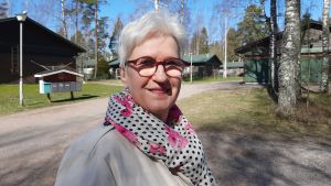 SDP-politikern Aila Pääkkö stöder hotellbygget. En kvinna som ler. I bakgrunden syns hus.