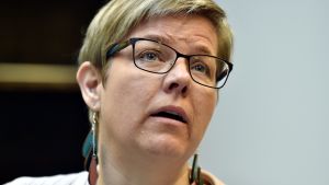Krista Mikkonen är ordförande för De grönas riksdagsgrupp. Närbild av Krista Mikkonen som har kort blont hår, glasögon och stora örhängen.