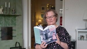 Lena Marander-Eklund har gjort en utredning om hemmafruars liv på 1950-talet. Lena Marander-Eklund sitter framför en kakelugn och läser ur boken Hemma och fru