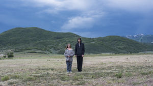 Charlie (Milly Shapiro) och Peter (Alex Wolff) vill bara vara två helt vanliga tonåringar. Charlie och Peter står bredvid varandra på ett öppet stor fält med höga berg i bakgrunden.