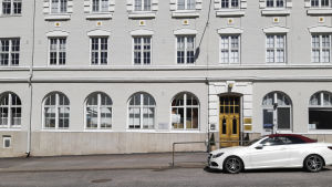 Daghemmet Domus ligger vid Brändövägen 6, men ska flytta. En vit byggnad framför en asfaltväg. En bil står parkerad framför byggnaden.