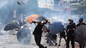 Demonstranterna kastade flaskor och tegelstenar. Demonstrant i Hongkong svarar på polisens tårgas med att kasta en tegelsten.