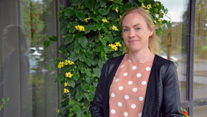 Turismkoordinator Niina Aitamurto säger att flygskamen inte är lika stor i Finland som i Sverige, men säkert påverkar en del.. Kvinnas står utomhus framför blommor och ett fönster till en byggnad.