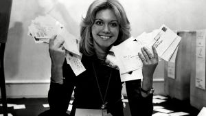 Olivia Newton-John kilpaili Euroviisuissa samana vuonna ABBAn kanssa. Olivia-Newton John laskee äänikirjekuoria Euroviisuissa 1970-luvulla mustavalkoisessa kuvassa.